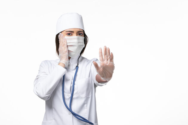冠状病毒防护正面图女医生穿着白色无菌医疗服 带口罩 因白色桌上有冠状病毒疾病大流行病毒covid-病毒冠状病毒成人