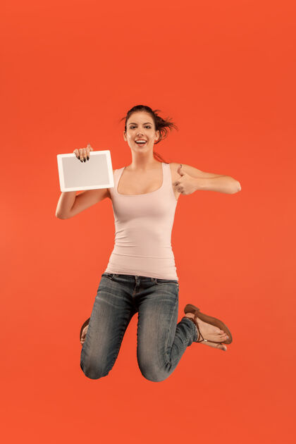 能源图片中的年轻女子在蓝色空间使用笔记本电脑或平板电脑小玩意 而跳跃跳跃科技服装