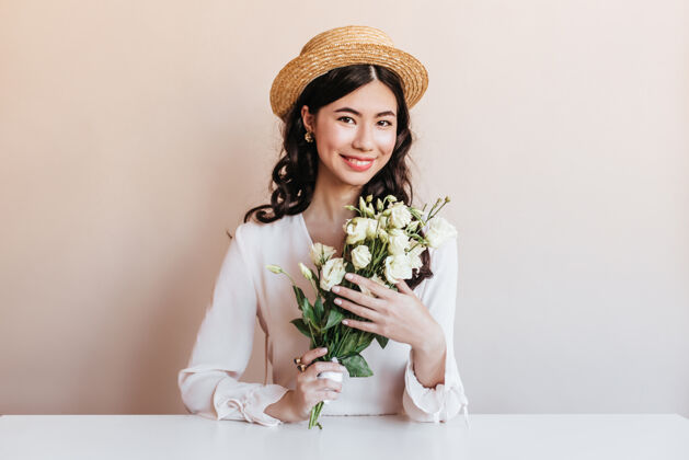 幸福欣喜若狂的韩国女人微笑着摆出鲜花的姿势令人高兴的是一些卷曲的亚洲女人拿着白色的桔梗中国花庆祝