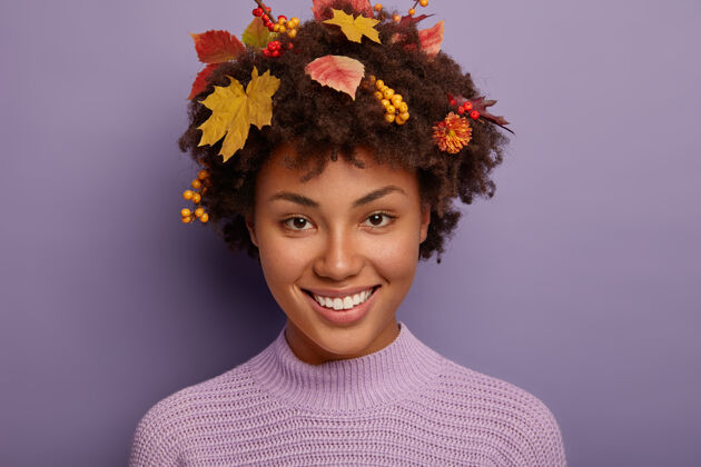 欢呼《秋高气爽的女人画像》在画室里写真 开心地看着相机 露出洁白的牙齿 卷发上秋天的植物 与紫色的画室墙壁隔离开来牙齿非洲年轻