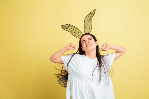 女性疯狂快乐 跳舞白人妇女作为一个复活节兔子在黄色工作室背景复活节快乐问候兔子蓝色漫画