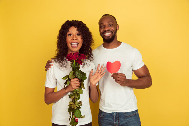 年轻花与心情人节庆典 黄色工作室背景上的一对快乐的非洲裔美国夫妇浪漫肖像情人节