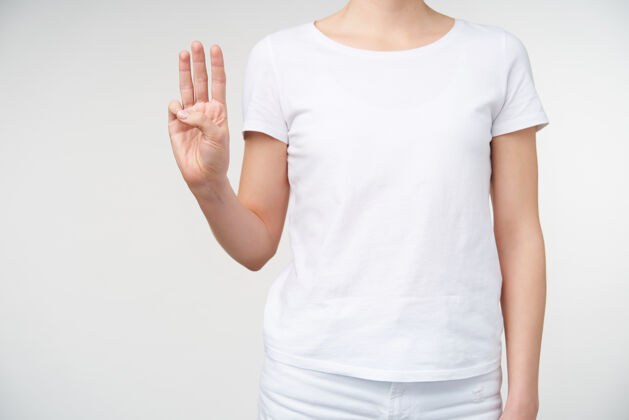 皮肤白皙摄影棚照片的年轻女子保持举手 形成字母w 而站在白色背景手语和人手的概念手指图形符号