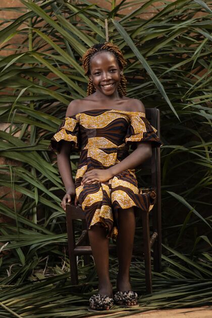肖像在椅子上摆姿势的满脸笑容的女孩村庄非洲孩子