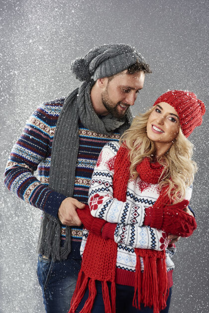 异性恋情侣站在暴风雪中的年轻夫妇拿着季节围巾