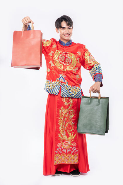 传统穿旗袍西服的男人微笑着从中国新年购物纸袋文化男人纸袋