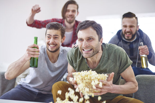 会议兴奋的男人们在电视上看比赛举手吸毒看电视