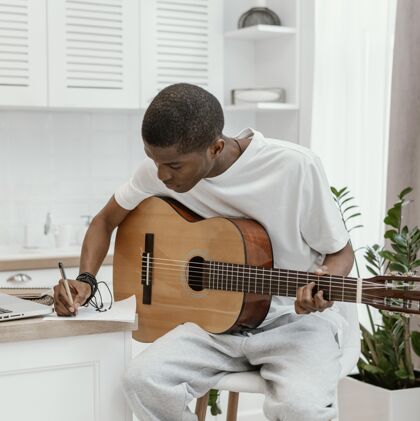 人才前视图男音乐家在家里弹吉他和写歌词技能创造者房子
