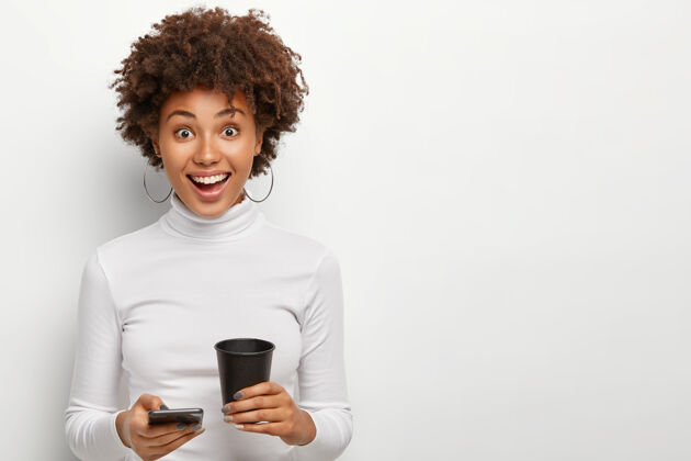 卷发摄影棚拍摄了一位穿着休闲服的美籍黑人妇女 在手机上查看电子邮件穿着科技正面