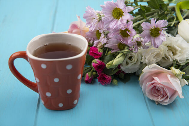 杯子一杯茶的俯视图 蓝色木质背景上有美丽的鲜花茶桌子花