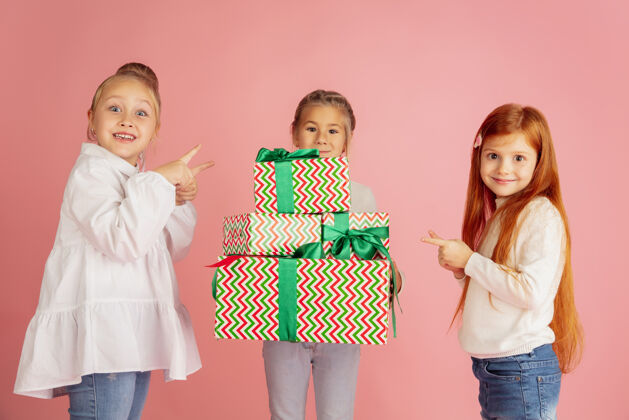 孩子在圣诞节期间送礼物和收到礼物一群快乐的孩子们在粉色工作室背景下欢庆2021年新年聚会 童年 快乐 情感家庭赠送赢家