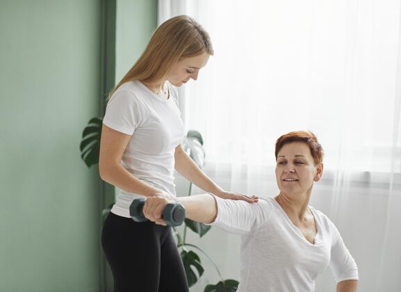 康复老年妇女在用哑铃进行体育锻炼老年人女人康复