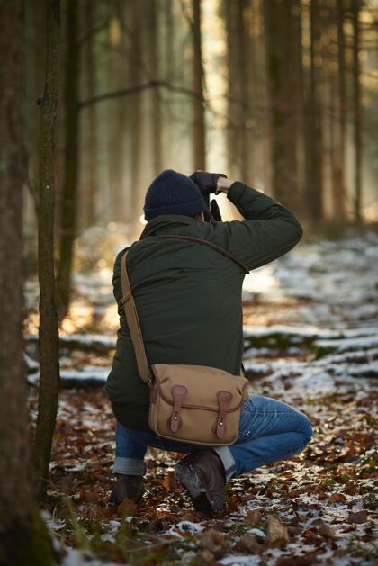 冰冻摄影师在一片被雪和树叶覆盖的绿树环绕的森林里拍照木蓝色风景