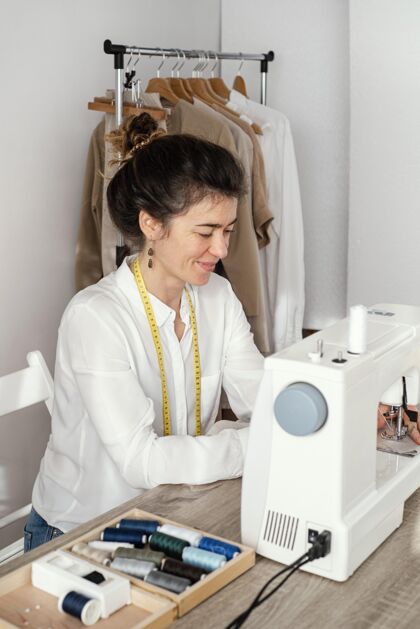 针线活女裁缝用缝纫机工作的侧视图服装缝纫机女装