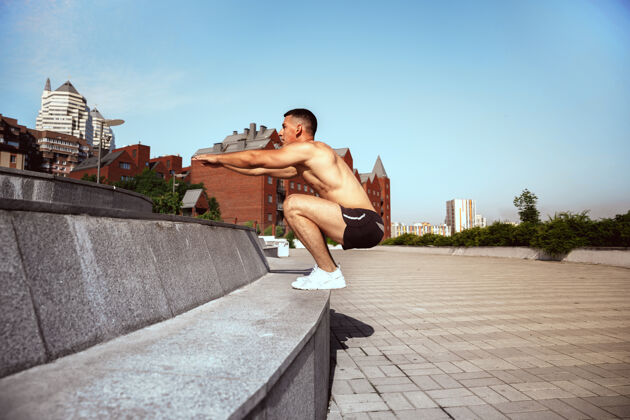 英俊一个肌肉发达的男运动员在公园里锻炼体操 训练 健身锻炼 柔韧性夏日城市在阳光明媚的日子背景场上积极健康的生活方式 青春 健美户外肌肉锻炼