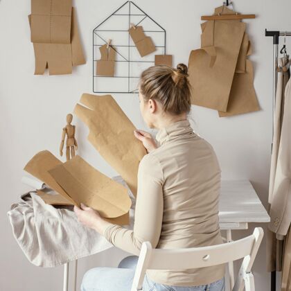 裁缝师后视图的女裁缝在工作室工作的模式昂贵的正方形服装