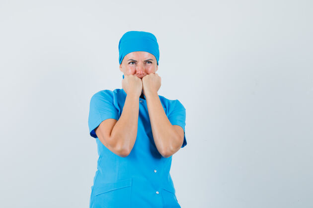 工作人员穿着蓝色制服的女医生情绪激动地咬着拳头 看起来很害怕 正面视图站年轻人恐惧
