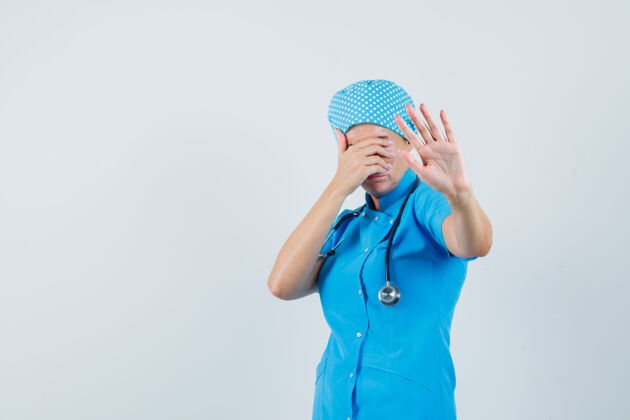 肖像女医生做停车手势 蓝色制服遮住眼睛 看起来很害怕前视图展示封面诊断