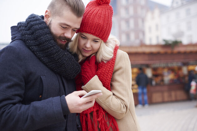 女人看看圣诞市场上的手机吧寒冷牙齿微笑圣诞市场