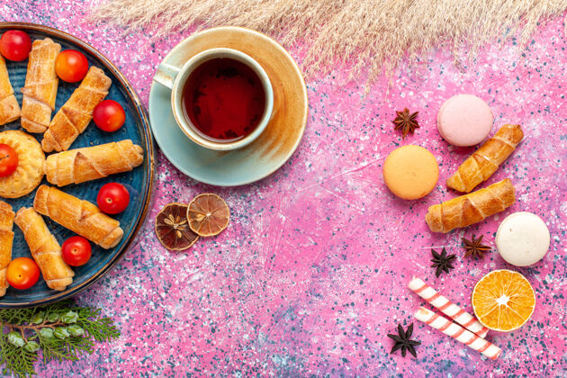百吉饼在浅粉色的桌子上 可以看到甜甜可口的百吉饼 法式马卡龙和一杯茶生的蛋糕法国