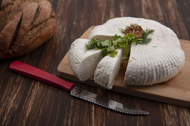 壁板侧视图feta奶酪在一个立场上与一把刀和一个面包在一个木制的背景饭菜羊奶木头