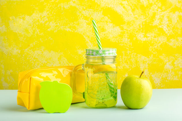 鸡尾酒正面是新鲜的鸡尾酒 绿色的苹果和黄色表面的笔盒闪亮的苹果食物