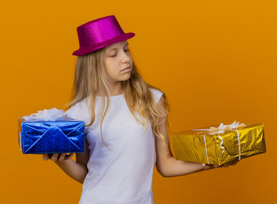 选择戴着节日帽子拿着礼品盒的漂亮小女孩节日站着盒子