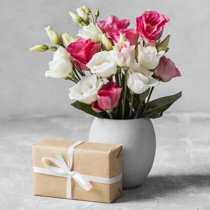 花束正面图：一束玫瑰放在一个花瓶里 旁边是一个包装好的礼物礼物安排春天