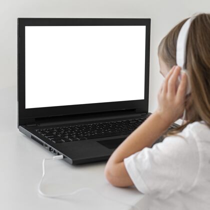 笔记本电脑小女孩用带耳机的笔记本电脑设备孩子爱好