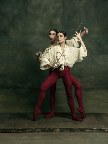 赤脚激情四射两个年轻的女芭蕾舞演员喜欢在深绿色的墙上拿着剑的决斗者高加索模特们一起跳舞芭蕾舞和当代舞蹈概念快乐一起芭蕾舞