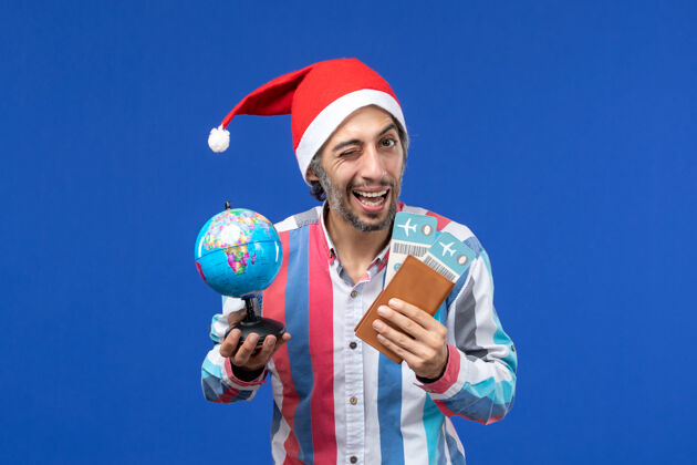 圣诞节前视图普通男性带门票和地球仪上蓝色地板颜色的节日新年机票天空足球