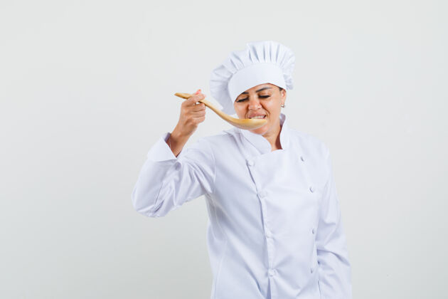 烹饪穿着白色制服的女厨师用木勺品尝美食服务举行新鲜