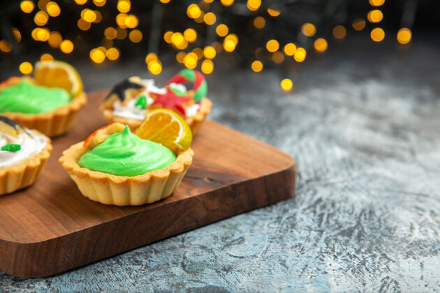 甜点前视图砧板上的小馅饼圣诞饰品深色表面圣诞灯排骨装饰品景观