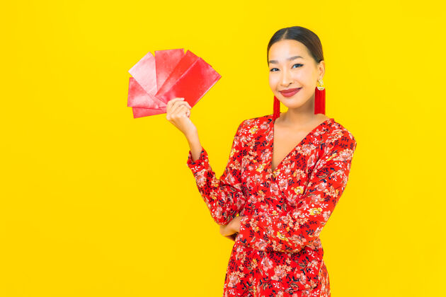 传统在黄色的墙上画一幅美丽的亚洲年轻女子拿着红包春天人类运气