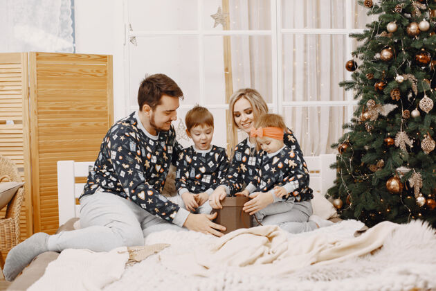 女人人们在为圣诞节修缮人们坐在床上一家人在节日的房间里休息树花环男人