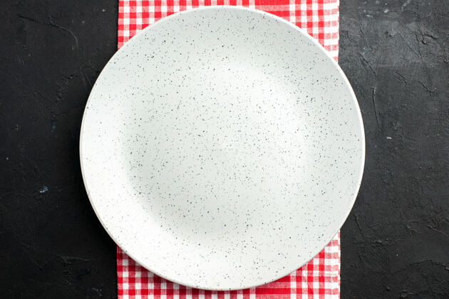 托盘顶视图白色圆板上的红色和白色方格餐巾在黑暗的桌子上全球座位盘子