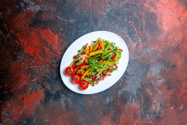 椭圆形俯瞰蔬菜沙拉椭圆形盘上黑暗的桌子上的自由空间番茄沙拉餐