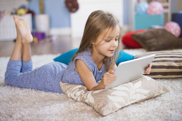 游戏在地毯上放着数字平板电脑的小女孩孩子童年向下看