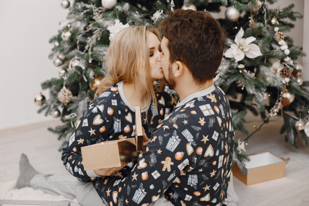 圣诞穿着圣诞老人装潢的人们穿着睡衣的男人和女人一家人在家里胡须关系拥抱