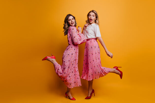 快乐两位女性朋友穿着红色高跟鞋的全幅肖像热情女士在一起的室内照片年轻享受表情