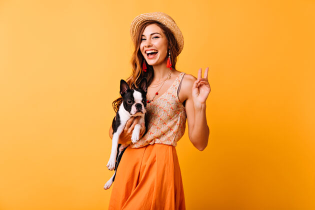 欢乐时尚的女孩抱着法国斗牛犬大笑乐观的红发女士和她的狗在工作室里放松休闲动物橙色