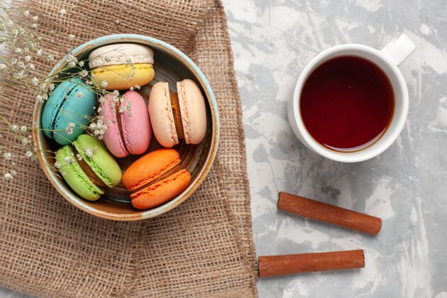 午餐俯瞰彩色法国马卡龙美味的小蛋糕和一杯茶在白色的桌子上颜色甜点茶
