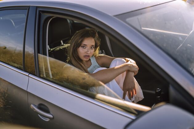 座椅一个美丽的年轻白人女性在一个领域的汽车前排座位摆姿势的水平镜头机械运输汽车