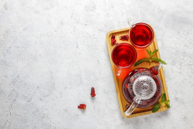传统热木槿茶在一个玻璃杯子和玻璃茶壶顶香料花瓣