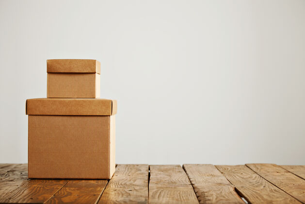 储存两个不同大小的米色瓦楞纸板未贴标签的盒子呈现在彼此的顶部 在白色上相互隔离盒子运输礼品
