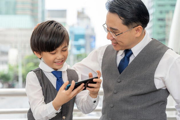 手机父子俩在市区商业区一起玩智能手机游戏儿童自由