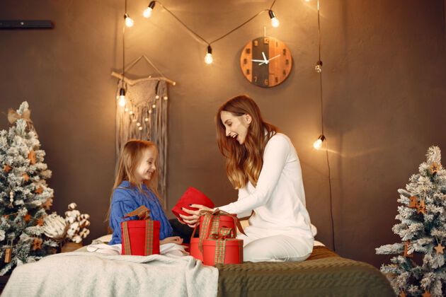 蓝色人们在为圣诞节做准备母亲在和女儿玩耍一家人在节日的房间里休息孩子穿着蓝色毛衣女人红色装饰