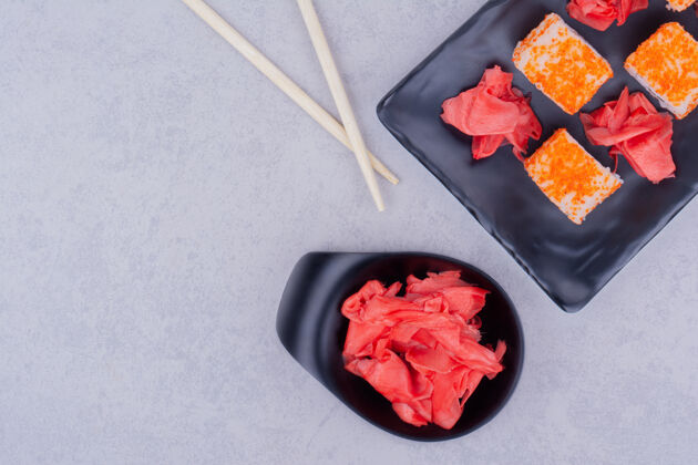 早午餐三文鱼卷和红腌姜放在一个黑盘子里美味产品亚洲