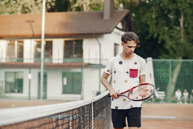 网球一个穿着t恤的快乐的年轻人一个拿着网球拍和球的家伙英俊健康动作