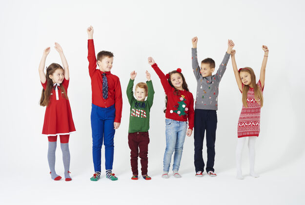 圣诞节时间孩子们站成一排举起手来的正面图庆祝爱乐趣